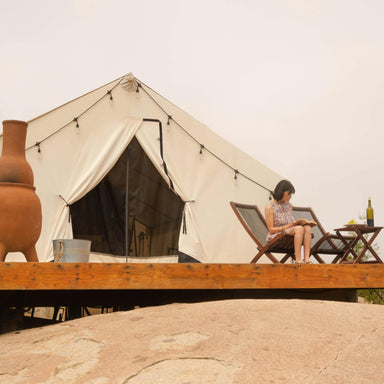 Wall Tent Canvas Camp woman on deck reading with grapes and wine