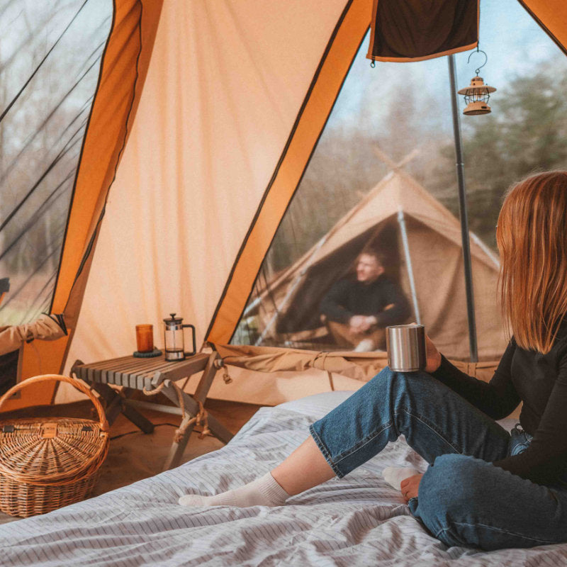 A Frame Tent Big Horn by Canvas Camp interior view woman drinking coffee on bed