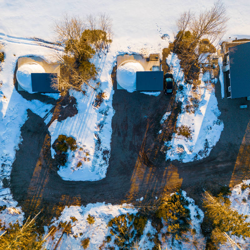 Stargazing Dome 23' Luna Glamping white birds eye view in woods with snow on concrete slab