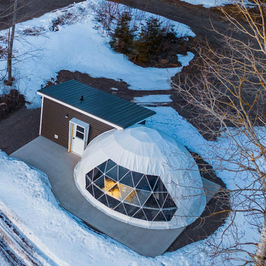Stargazing Dome 23' Luna Glamping white in forest with snow on concrete slab