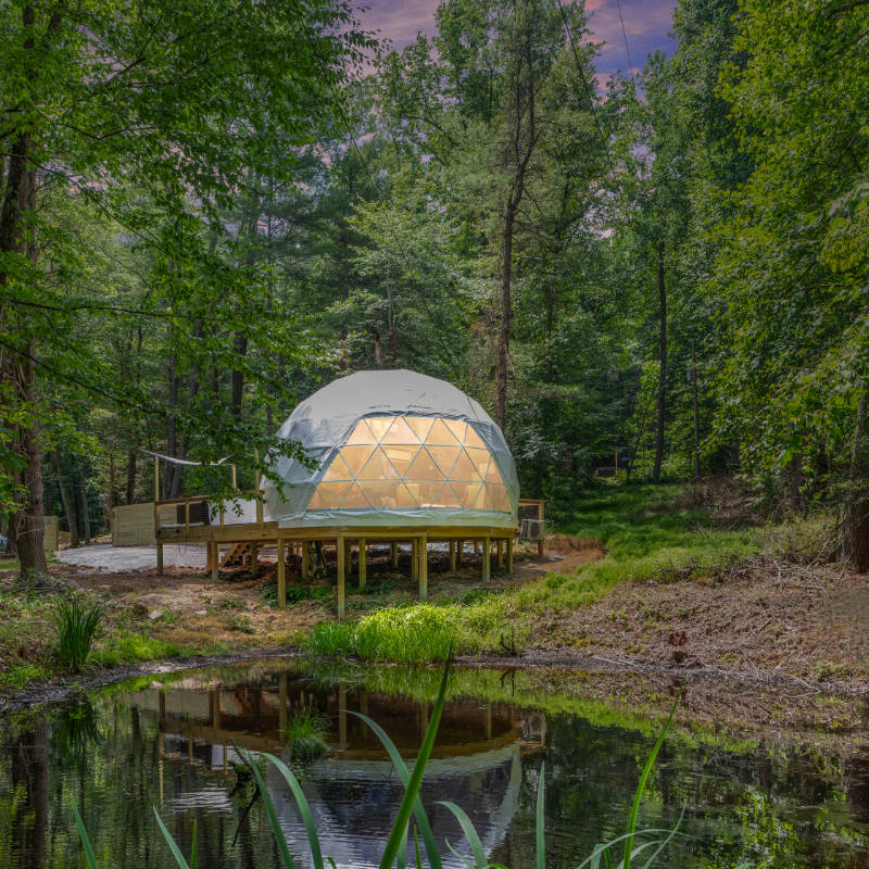 Stargazing Dome 26' Luna Glamping in white on wood deck by pond at night