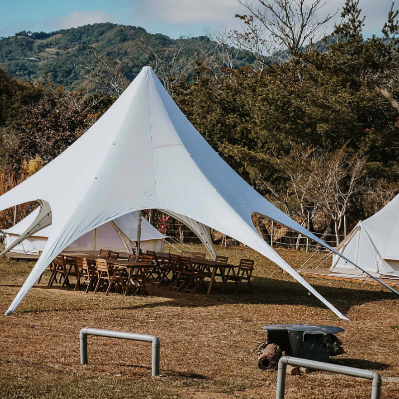 Starshade Event Tent by CanvasCamp  Luxury Outdoor Canopy during the day with tables and chairs on brown grass