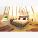 Teepee Tent by Nomadic Tipi Makers interior view with wood floor bed and side table