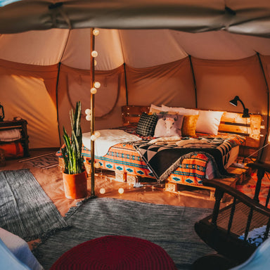 Yurt Tent Temple Apex by Canvas Camp interior view from front door with bed on wood pallets and plant