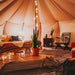 Yurt Tent Temple Apex by Canvas Camp interior view from front door with bed on wood pallets and plant with lights